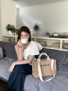French style straw tote bag with PARIS embroidery shown in a relaxed lifestyle setting