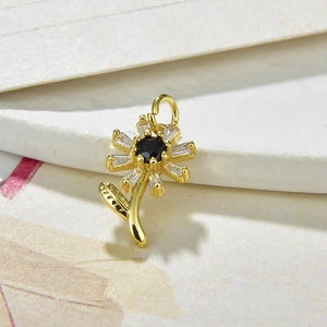 Macro view of gold flower pendant with black zircon center and clear petals