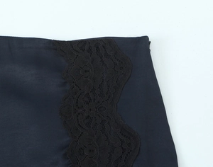 Detailansicht des schwarzen Satin-Minirocks mit filigranem seitlichem Spitzenbesatz