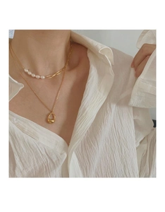 Close-up of layered gold pearl chain necklace with waterdrop pendant on a white shirt