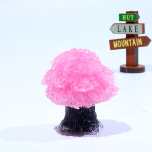 Detailed view of pink crystal tree ornament with dark natural stone base and clear resin finish