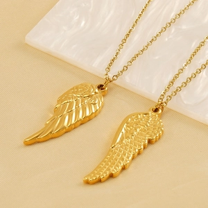 Golden angel wing pendant necklace with rose engraving detail on warm background