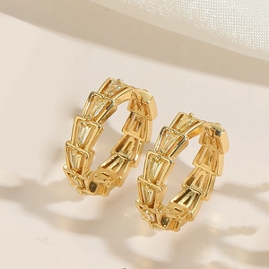 Detailed close-up of gold hoop earrings with tiered scale design and baguette zircons