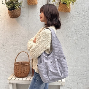 Detail of grey gingham canvas tote bag featuring functional snap-button front pockets