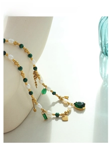 Detail of beaded necklace with pearls, green malachite beads and golden heart pendants