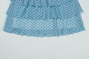 Détail d'une robe en tulle bleu clair à pois avec volants superposés et tissu léger
