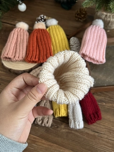 Close-up of colorful mini knitted Christmas hats with white pom-poms on wooden background