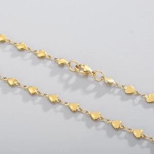 Close-up of golden stainless steel heart-shaped chain bracelet with lobster clasp