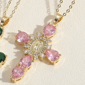 Close-up of golden cross necklace with pink pear-cut stones and Virgin Mary medallion