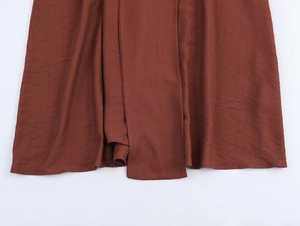 Detailed view of the reddish-brown dress hem featuring a natural crinkle texture fabric