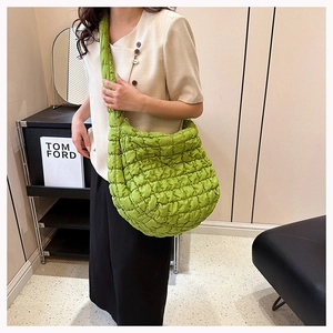 Close-up of bright green quilted cloud bag featuring pleated puff texture and wide strap