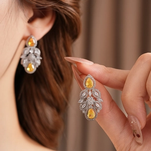 Detail of vintage silver earrings with yellow teardrop stones and zircon accents on a model