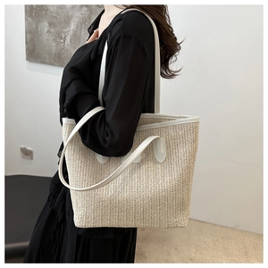 Détail du tissage en paille et bordure en similicuir blanc sur un grand sac fourre-tout