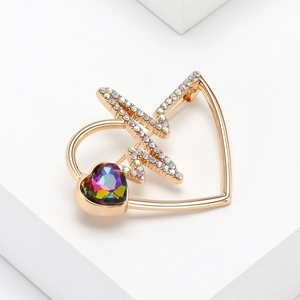 Macro shot of gold heart brooch with colorful rhinestones on a white pedestal