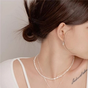 Close-up of elegant double-layered silver pearl necklace and matching stud earrings on model