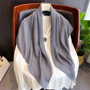Detail of a soft grey linen shawl draped over a wooden chair with a white top