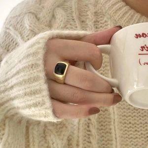Detailed view of a gold vintage ring featuring a square black gemstone and textured band