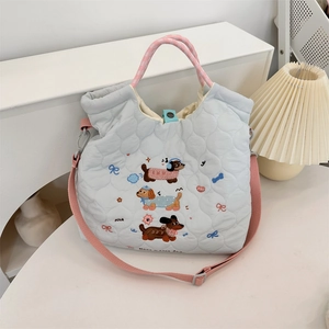 Detailed view of light blue quilted bag with cute puppy embroidery and woven handles