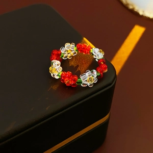 Macro detail of multi-colored beaded flower ring resting on a vintage brown jewelry box