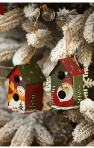 Gros plan d'une maison de Noël en métal de 10 cm suspendue sur une branche enneigée