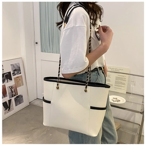 Detail showing the white tote bag with black piping and gold chain leather strap
