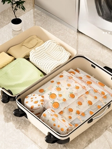 Mesh laundry bags with orange fruit prints neatly organized inside a white suitcase