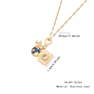 Detail showing stainless steel necklace with airplane, globe, and camera pendants