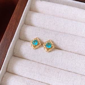 Détail de boucles d'oreilles fleurs vintage avec pierres bleues dans un écrin en bois