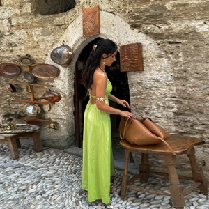 Close-up of a neon green satin maxi dress showing the backless halter design and smooth texture