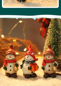 Close-up of three mini Christmas snowmen figurines with bells and gifts for table decor