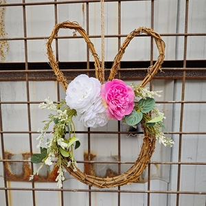 Detail of bunny-shaped rattan wreath featuring white and pink roses for Easter decor