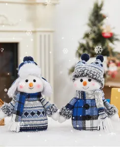 Close-up of plush snowman figurines with blue plaid fabric and warm holiday knitwear