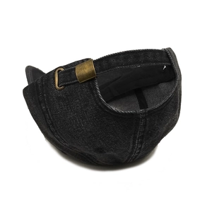 Detail of adjustable antique bronze metal buckle on black washed denim baseball cap