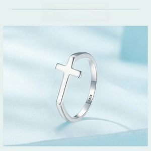 Macro shot of S925 sterling silver cross ring showing the hallmark on light blue surface