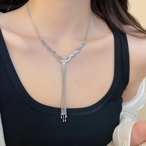 Detail of silver tassel necklace with wavy metal texture and beads on a model