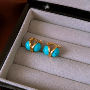 Macro view of vintage gold earrings with blue resin stones in a premium jewelry box