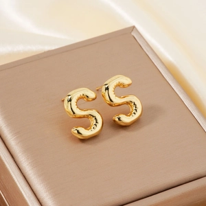 Polished gold balloon initial S stud earrings on elegant silk jewelry box lid