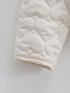 Detail of white padded jacket showing delicate heart-shaped quilting and cuffed sleeve