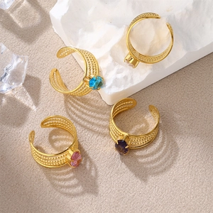 Macro shot of gold-plated woven rings set with colorful zircon stones on textured decor