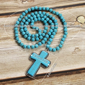 Detail of 8mm turquoise beaded prayer necklace with cross pendant on wood background