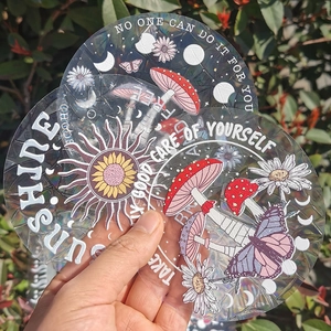Macro shot of holographic suncatcher stickers with mushroom and butterfly patterns
