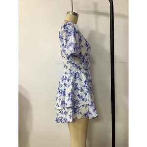 Detail view of double-layered ruffled hem on a blue floral mini dress with puff sleeves