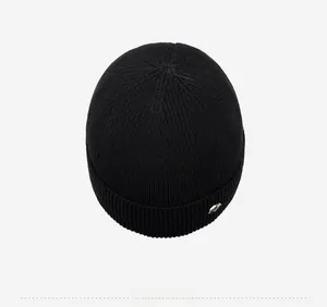 Top down view of black ribbed knit beanie featuring silver metal logo detail on the cuff