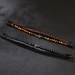 Multi-layer leather bracelet with cross charm and tiger eye beads on black background