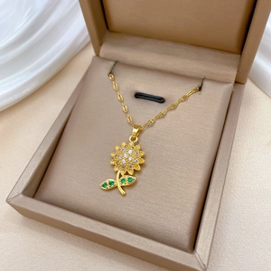 Luxurious gold sunflower necklace with white and green crystals in a beige jewelry box