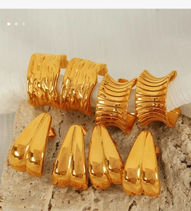Macro shot of 18K gold C-shape earrings with irregular lava texture on stone base