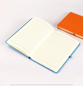 Detail of hardbound notebooks with elastic closure showing lined pages in blue and orange