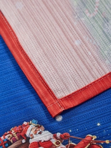 Close-up of woven Christmas placemat with red trim and Santa Claus embroidery detail