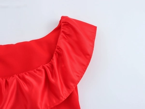 Gros plan sur le décolleté rouge à volants montrant le tissu satiné lisse et les textures