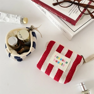 Detailed top view of striped canvas makeup pouches with lipstick and cosmetics on white desk